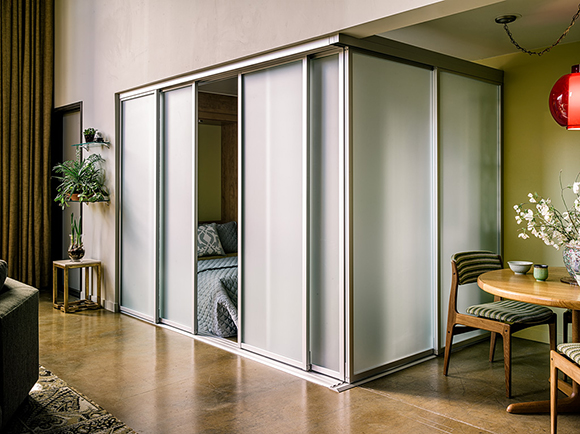 Guest bedroom with translucent partitions closed, allowing for privacy in a loft bedroom space