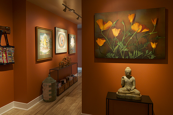 Entryway in oranges and browns with a Buddha statue under a canvas of poppies