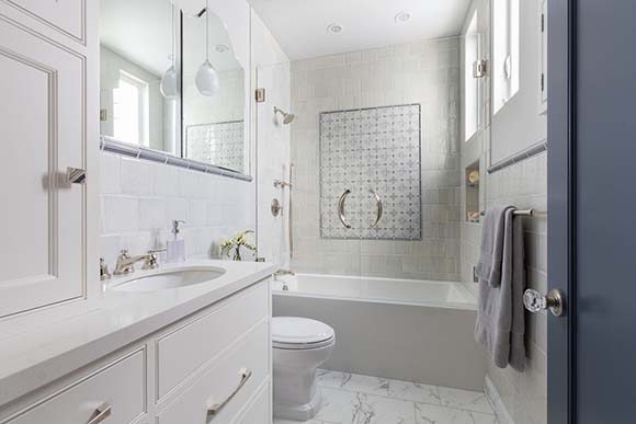 Photo of a light, airy bathroom with white and cream tiling accented with minty green, white fixtures, and plenty of open space.