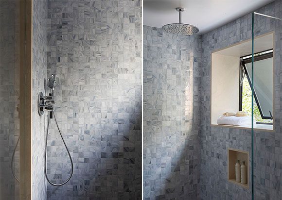 Two side-by-side images of a San Francisco master bathroom, with multi-colored blue mosaic tiling on walls, warm tan tiling on floor, handheld showerhead at left wall, overhead rain showerhead, and right image shows operable window that swings open bottom out