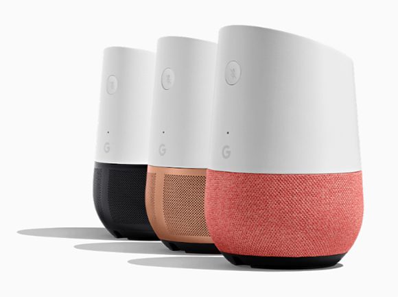 Photo of 3 Google Home speakers lined up in a staggered row, with the rear speaker having a black bottom and white top, bearing the G logo for Google. The center speaker is copper in color with white on top, and the front speaker is an orangey brick-red with white. The tops of the speakers are angled to create a flat surface that leans toward the user, and near the top is a single button on each speaker, where the "mic off" graphic is placed. It's a simple, elegant design.