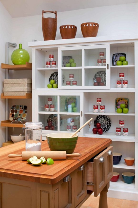 A closeup on the kitchen reveals deep drawers under the island. Behind, a mix of open and closed shelving keep kitchen tools close at hand. Place pretty, infrequently-used items on the top surface.