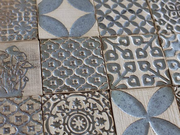 Photo of 12 different styles of ceramic tiles, all in off-white and blue-grey tones, with multiple geometric shapes and patterns available.