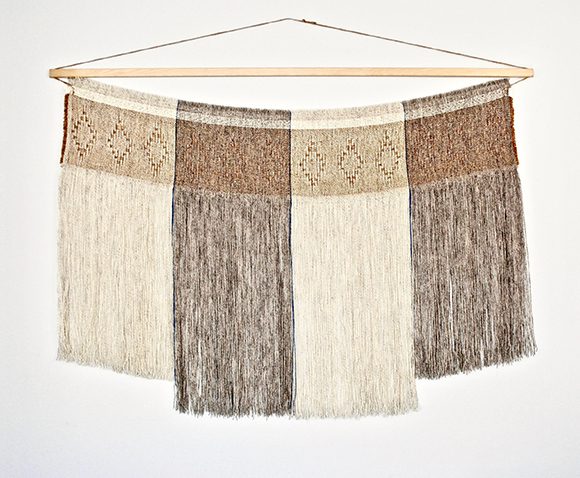One of a kind wall-hanging made with a woolen warp and a linen/cotton/wool weft in a textured lace-style distorted diamond, with the unwoven threads of dark brown and off-white hanging down below in alternating stripes.
