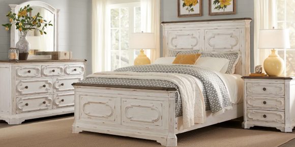 Photo of a bedroom suite in all white, distressed finish, country style, with a matching side table, chest of drawers, and bed with headboard and footboard.