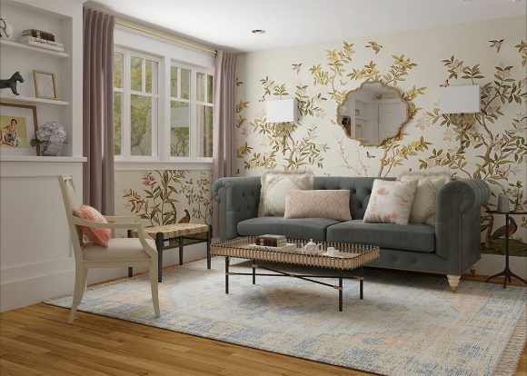 Gold botanical wall art is wrapped around one corner behind a moss-green sofa in an off-white living room with lilac curtains offsetting white window sills. Tastefully styled bookshelves are off to the left, while a bench and chair face into the coffee table set for tea. A large geometric mirror is centered on the botanical wall above the sofa. All the furniture exhibits a square shape and strong lines softened with luxurious fabrics.