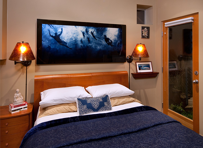Cherry sleigh bed and rich blue tones make for a cozy bedroom in this tiny bedroom. Wall sconces and wall shelf save space in this small bedroom.