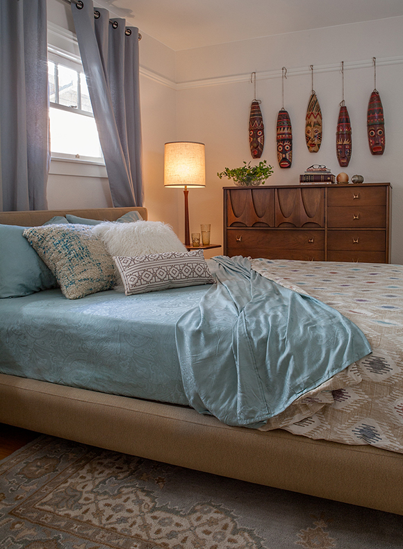 Light blues, creams and whites counterpoint the wooden mask collection in this San Francisco vintage bungalow bedroom