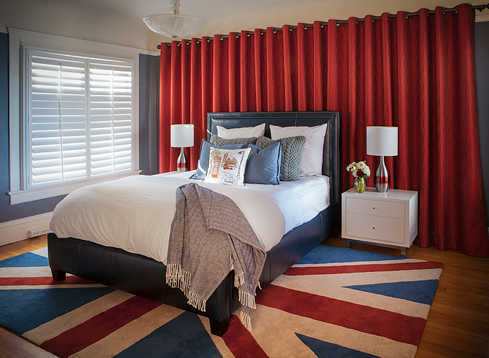 Contemporary bedroom by Kimball Starr with Union Jack rug, red drapery, and blue leather bed.
