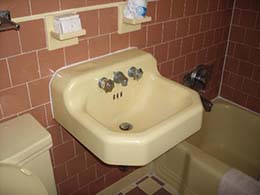 Photo of an out-of-date, motel bathroom with mauve tiling, pink sink and bathtub.