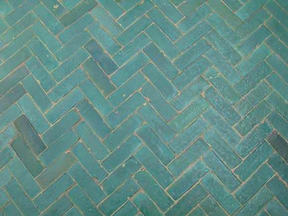 Closeup of herringbone patterned tiling with variations on the same sea-green color as the prior images.