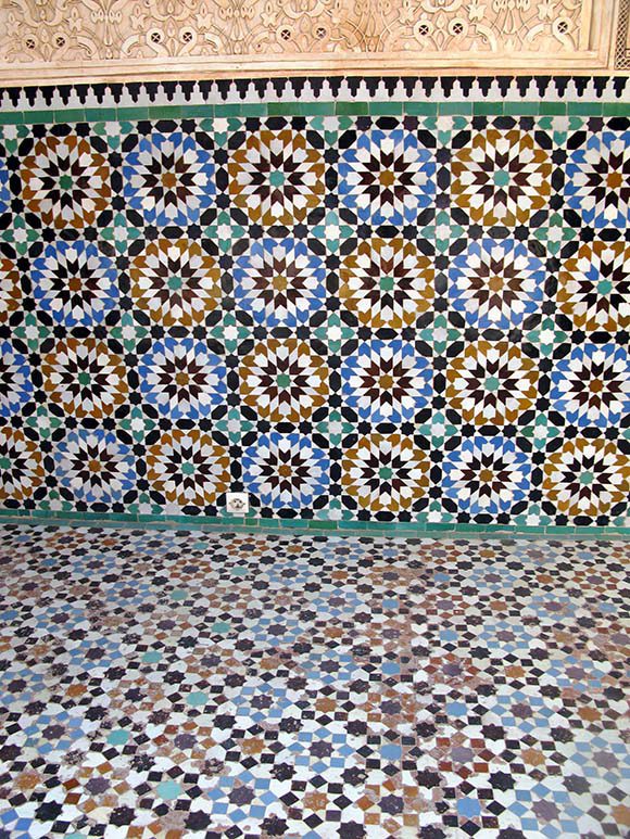 View of circular geometric tiling patterns on the wall and floor in yellow, green, blue, black and white.