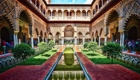 Photo of The Alcazar at Seville, Spain with columns and central courtyard full of plants and flowers