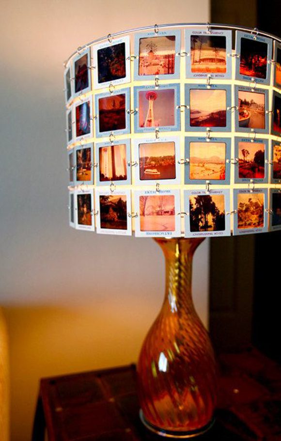 Photo of a glass lamp in orangey- red, featuring a hand-made lampshade made of 4 rows of photography slides featuring travel, landscape, and family scenes.