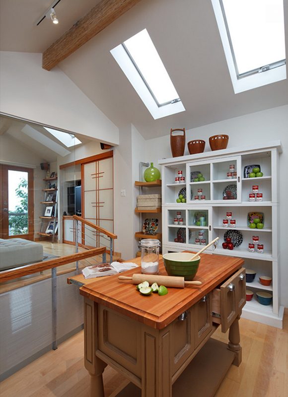 A small kitchen space benefits from a butcher-block surface island, with a pull-out work surface, and plenty of open and closed storage nearby.