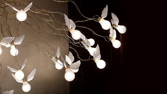 Lightbulbs seem to fly away from their wired centerpiece in the chandelier, each with a small pair of white wings attached at the base of the bulbs.