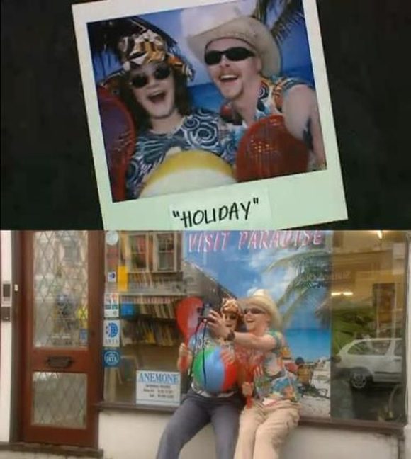 Scene from the television series "Spaced" showing a couple taking fake holiday photos in front of a travel storefront window. The Polaroid shows them in front of the tropical scene in hats and sunglasses, labeled with the word "Holiday".