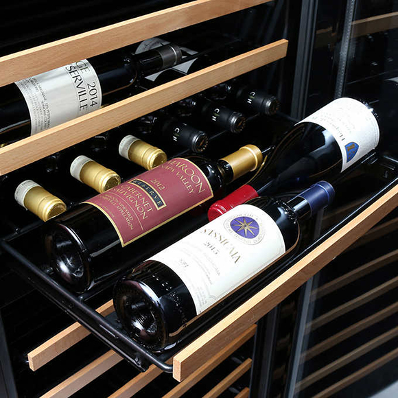 Closeup image of a pull-out wooden and metal rack of wines, bottles facing opposite directions to conserve space for wine storage.