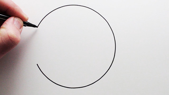 Photo of a person drawing a circle with a black pen.