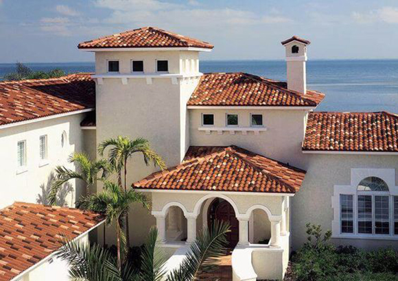 Colorful terracotta roof tile in warm reds, oranges, browns, and whites on a Mission-style home near the ocean in California.
