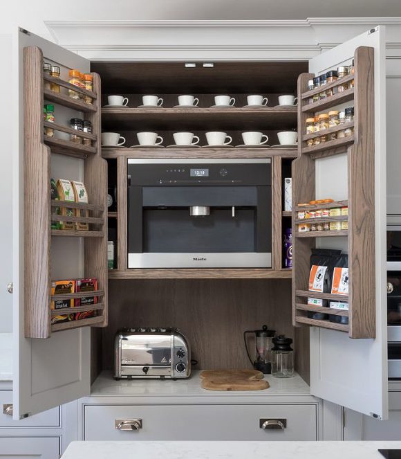 A custom shite cabinet filled with a Miehle coffee machine, wooden racks for tea and coffee, and on the counterspace, a toaster and French press, that all close away inside the cupboards.