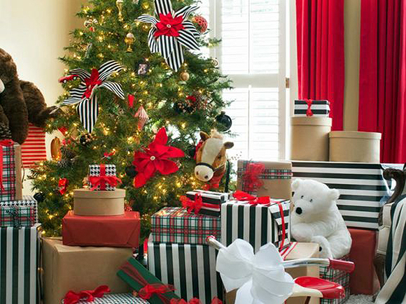 Black and white striped gifts under a tree alternate with red, green and white plaid wrapped gifts, and a few in plain red or brown. Red pointsettas on the tree are made more visible with black and white striped ribbon. Red curtains line the windows in the background.
