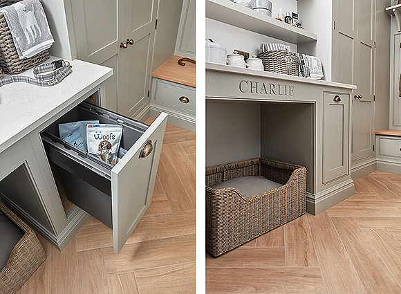 A tall and deep drawer is pulled out on the left to reveal dog food and treats underneath an off-white countertop near double cabinet doors, while the right image shows a wicker basked tucked underneath the desi, with the capital letters CHARLIE carved into the head of the counter. Above are baskets and jars of supplies. Tan herringbone wooden floors tone with the top of a built-in seat nearby in warm beige.