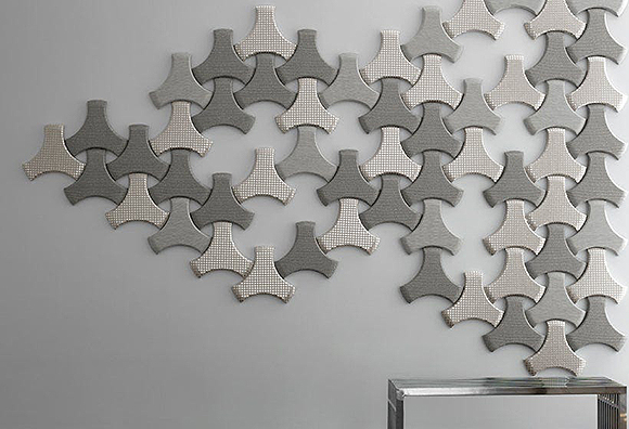 Multiple triangular shapes in different colors of grey with and without patterning up on a wall to reduce excess sound.