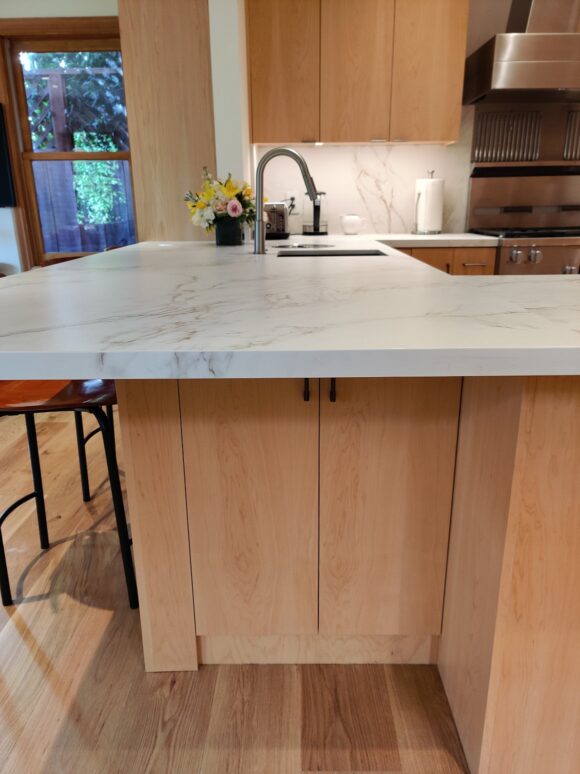 A hidden under counter double door storage cabinet allows infrequently used items to remain accessible, utilizing all the space under an L-shaped counter that would normally be dead space. The drinks and food prep sink and faucet are visible on this counter end also.
