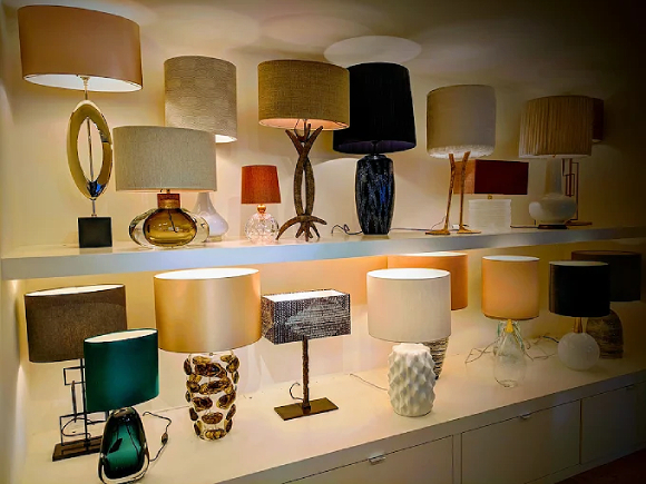 Two shelves full of different colors, sizes, and styles of tabletop lamps